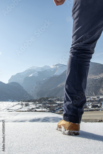 Leg of a tourist in a yellow boot and blue jeans against the backdrop of mountains