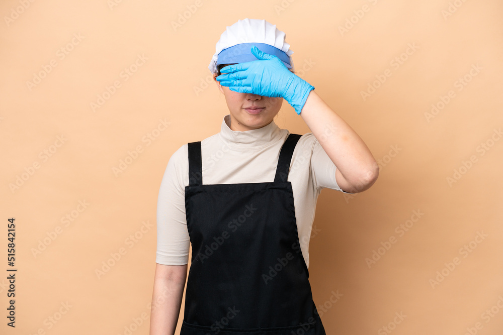 Young Chinese Fishmonger woman wearing an apron and holding a raw fish isolated on pink background covering eyes by hands. Do not want to see something Young Chinese Fishmonger woman wearing an apron and holding a raw fish isolated on pink background covering eyes by hands. Do not want to see something