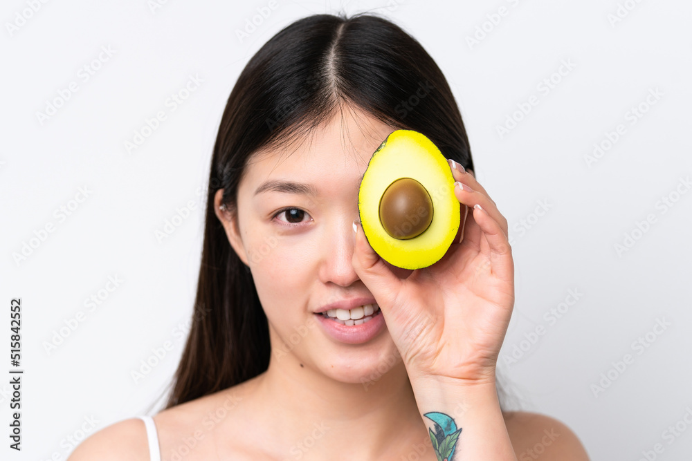 Young Chinese woman isolated on white background holding an avocado while smiling. Close up portrait Young Chinese woman isolated on white background holding an avocado while smiling. Close up portrait