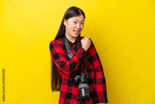 Young photographer Chinese woman isolated on yellow background celebrating a victory © luismolinero