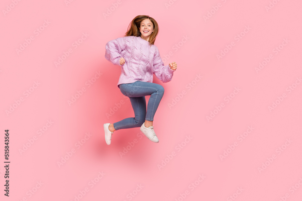 Photo of pretty adorable girl dressed knitted pullover running fast jumping high isolated pink color background Photo of pretty adorable girl dressed knitted pullover running fast jumping high isolated pink color background