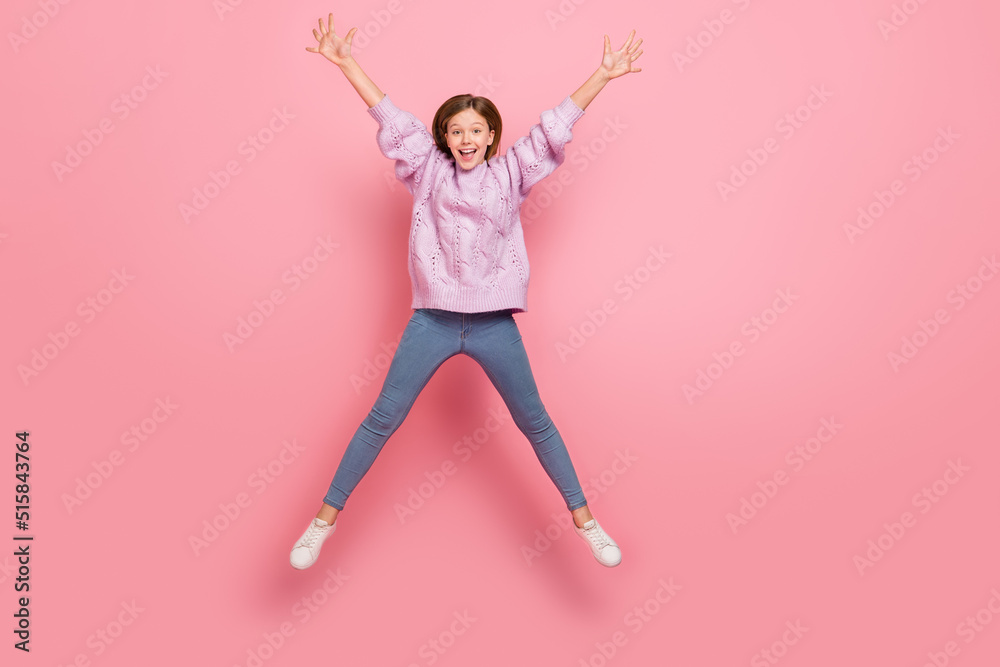 Photo of cute excited girl knitwear sweater jumping high like star isolated pink color background Photo of cute excited girl knitwear sweater jumping high like star isolated pink color background