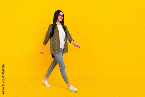 Full body photo of nice millennial lady go wear spectacles shirt jeans shoes isolated on yellow background