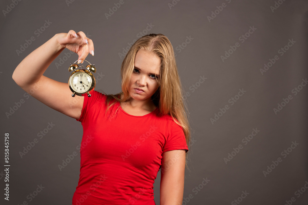 Tired woman standing on dark background with clock Tired woman standing on dark background with clock