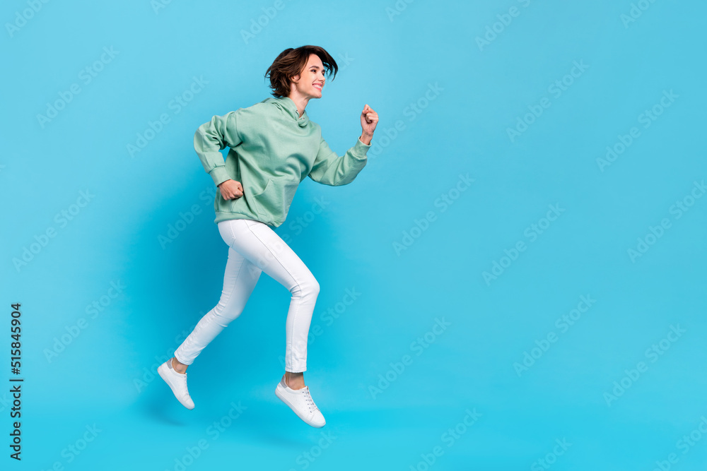 Photo of pretty adorable woman wear green sweatshirt running fast empty space isolated blue color background Photo of pretty adorable woman wear green sweatshirt running fast empty space isolated blue color background