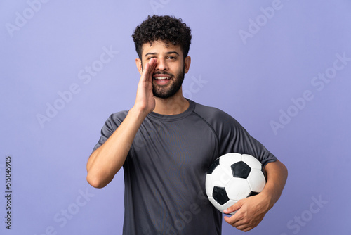 Handsome Moroccan young football player man over isolated on purple background shouting with mouth wide open