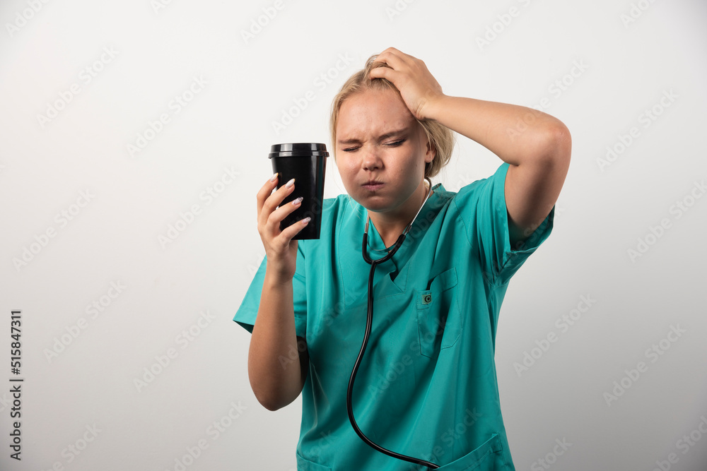 Young doctor with coffee having headache on white background Young doctor with coffee having headache on white background