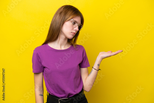 Young English woman isolated on yellow background holding copyspace with doubts