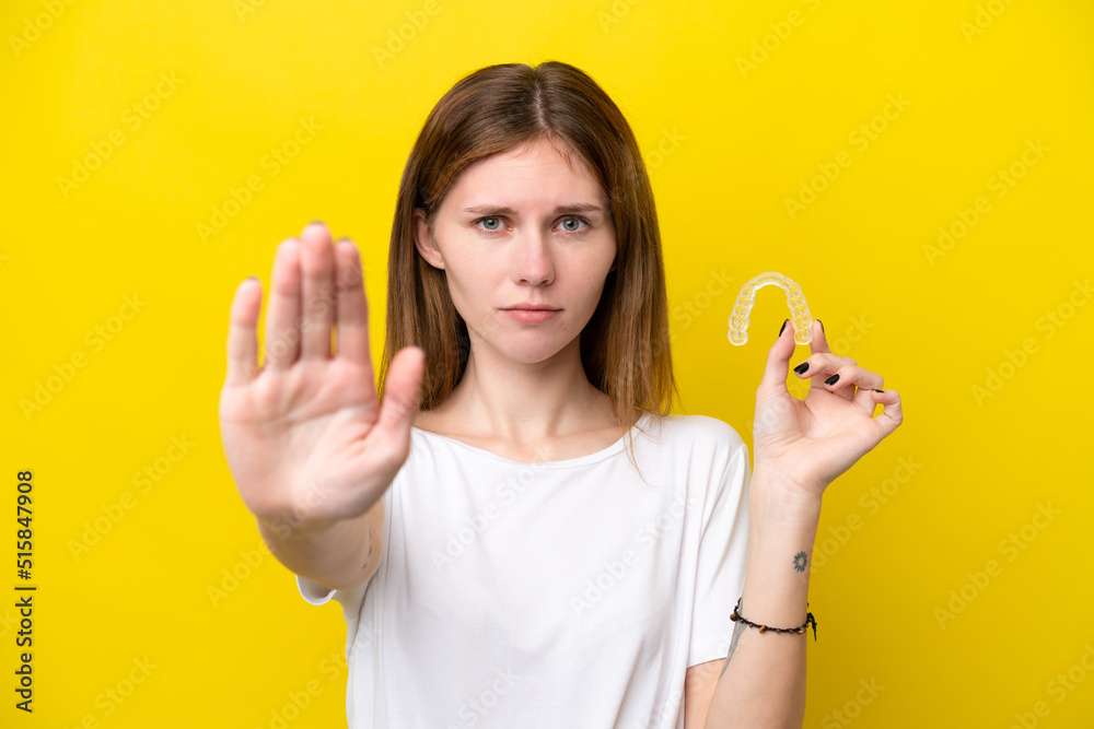 Young English woman holding invisible braces making stop gesture