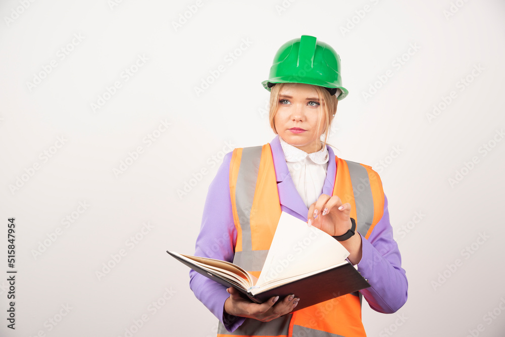 Young female builder in helmet with tablet on white background Young female builder in helmet with tablet on white background