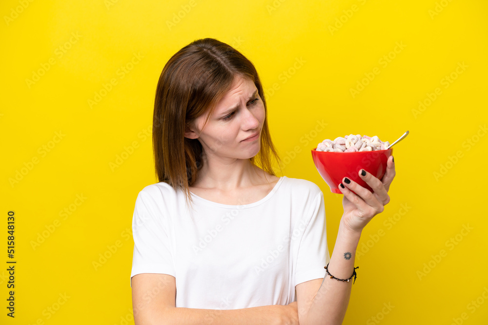 Young English woman holding cup of coffee isolated on yellow background with sad expression Young English woman holding cup of coffee isolated on yellow background with sad expression