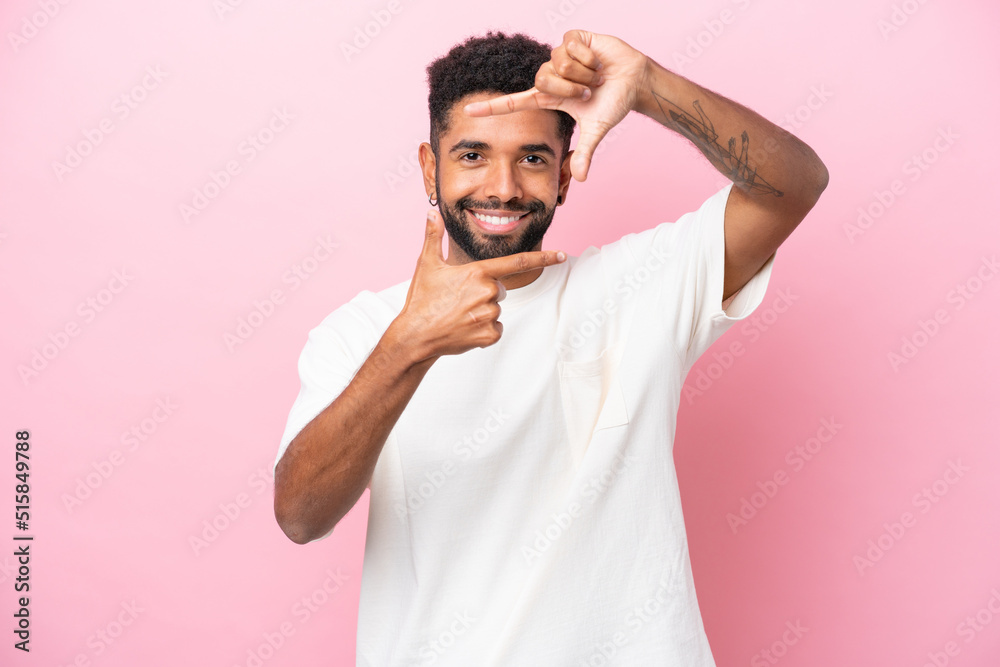 Young Brazilian man isolated on pink background focusing face. Framing symbol Young Brazilian man isolated on pink background focusing face. Framing symbol