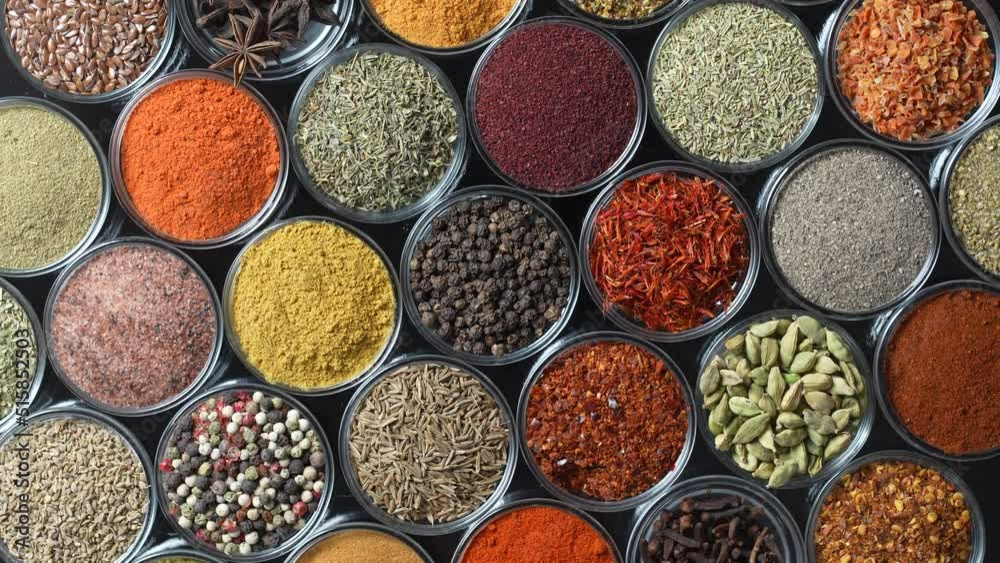 Assortment of aromatic spices, seeds and dry herbs for cooking food on background rotating in smal glass bowls rotating, close up, top view