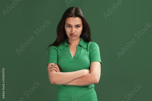 Portrait of beautiful young girl posing isolated over green studio background. Offended look