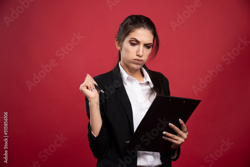 Young businesswoman checking avaible dates on red background photo