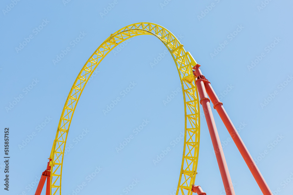 A fragment of a roller coaster against the blue sky. Arc-shaped metal beam structure on props A fragment of a roller coaster against the blue sky. Arc-shaped metal beam structure on props