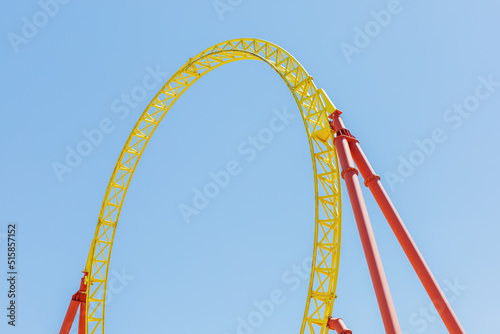 A fragment of a roller coaster against the blue sky. Arc-shaped metal beam structure on props