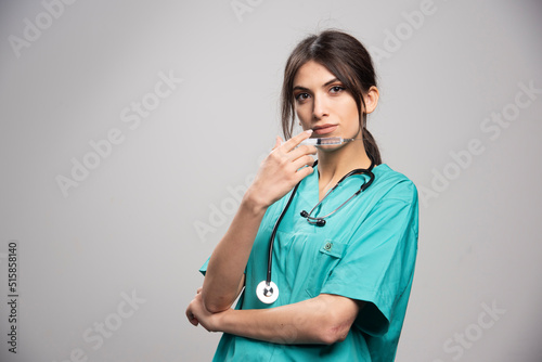 Female doctor posing with syringe on gray background