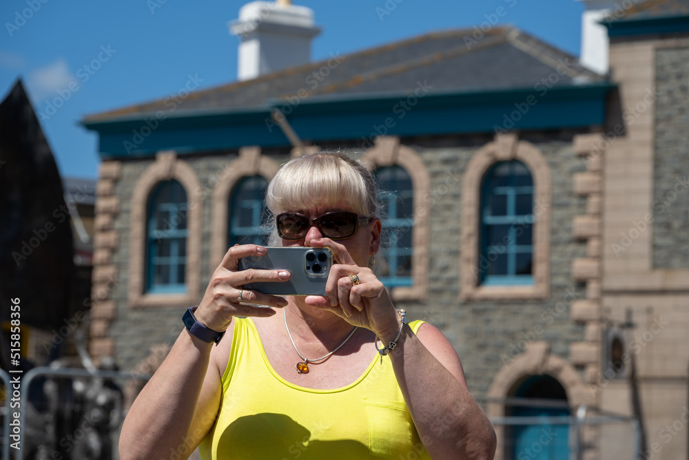 Mature woman on holiday taking photographs on a mobile phone.