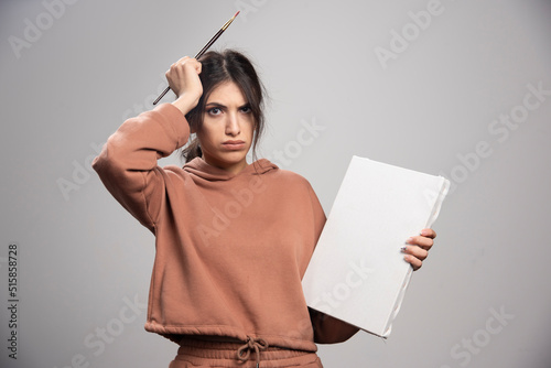 Fényképezés Young woman holding paint brushes and canvas