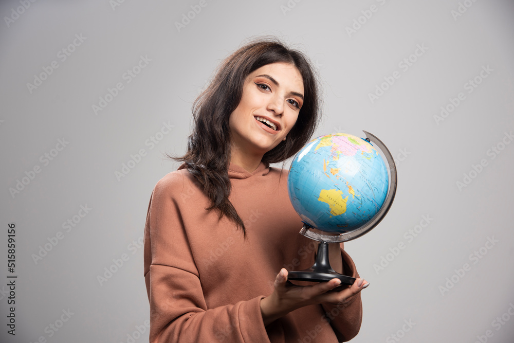 Brunette woman holding globe on gray background Brunette woman holding globe on gray background