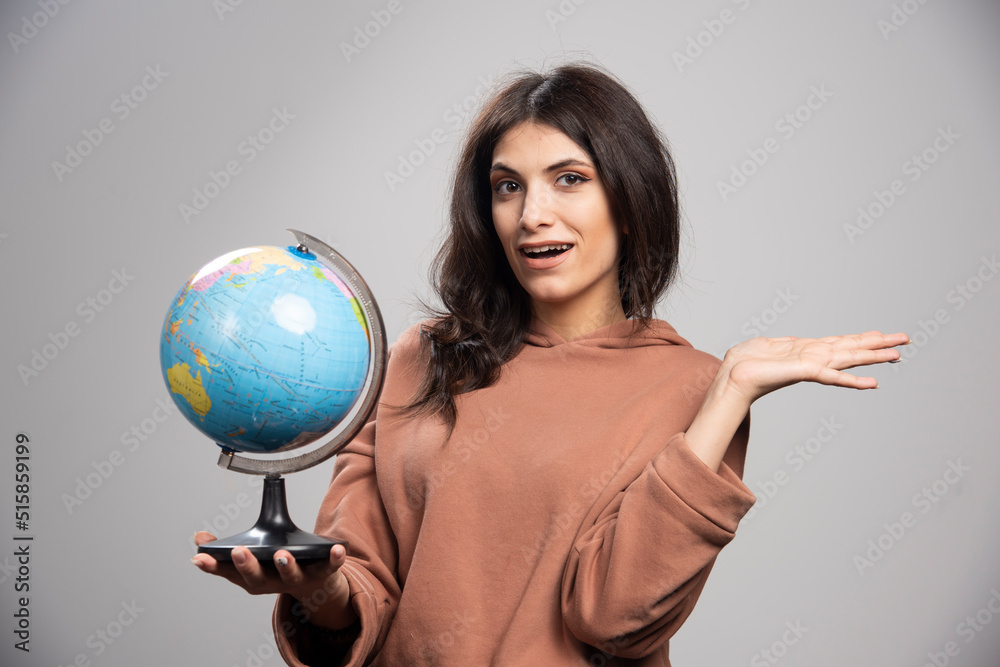 Brunette woman holding globe on gray background Brunette woman holding globe on gray background
