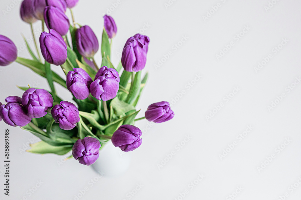 Fresh picked purple tulips in a vase on a solid white surface