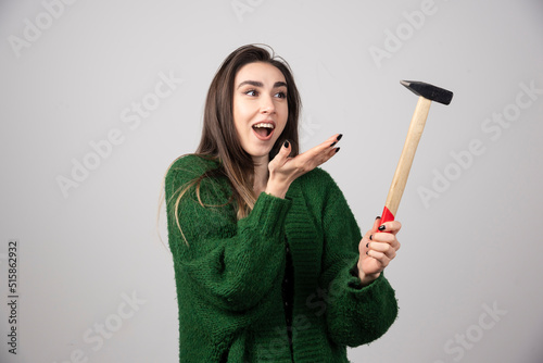 Young woman holding hammer in hands on a gray background