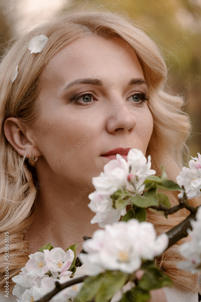 Adult blonde woman portrait enjoying flowering tree in spring garden Adult blonde woman portrait enjoying flowering tree in spring garden
