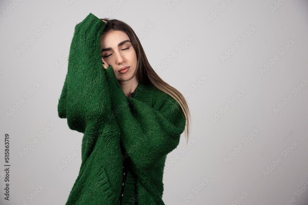 Young woman in green sweater sleeping on gray background Young woman in green sweater sleeping on gray background
