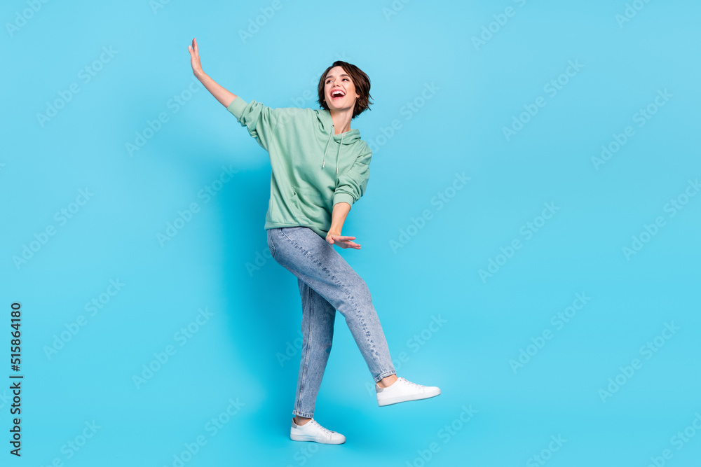 Full size photo of nice millennial brunette lady dance wear pullover jeans sneakers isolated on blue background