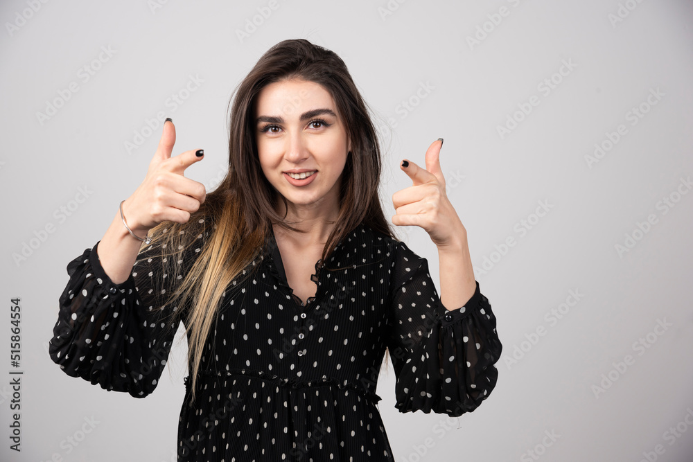 Portrait of woman pointing at camera on gray background Portrait of woman pointing at camera on gray background
