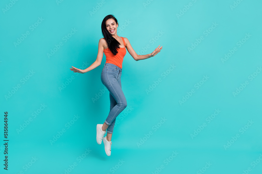Photo of sweet adorable lady dressed red tank top walking jumping high empty space isolated turquoise color background