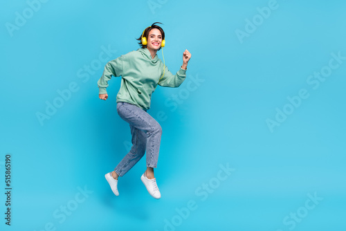 Full body profile photo of sweet young brunette lady run wear headphones pullover jeans shoes isolated on blue background