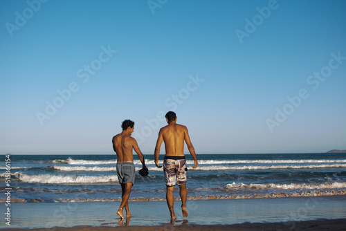 Two athletic friends entering the sea chatting with each other photo