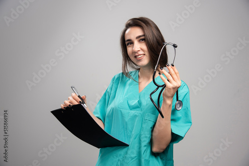 Smiling doctor holding stethoscope on gray background photo