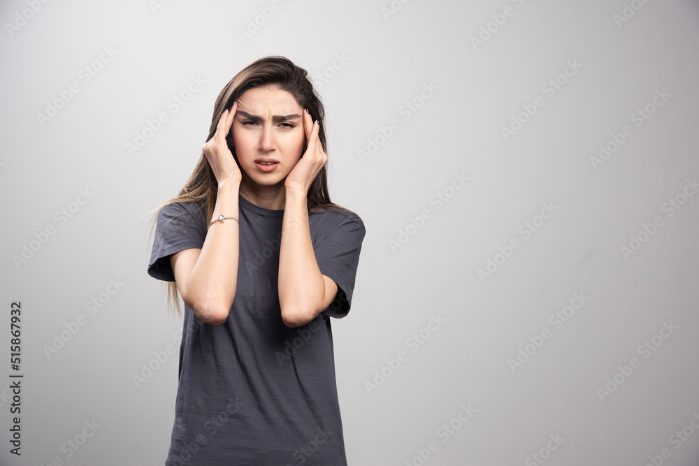 Young woman standing and touches his head in pain Young woman standing and touches his head in pain