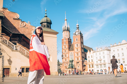 woman traveler covered with poland flag at the center of Krakow town