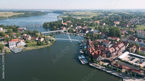 Mikolajki, Poland - Aerial bird view flight over the pedestrian bridge most wiszacy of the touristic city in Warmian Masurian with romantic houses along the sea and tiny ships and yachts in summer photo