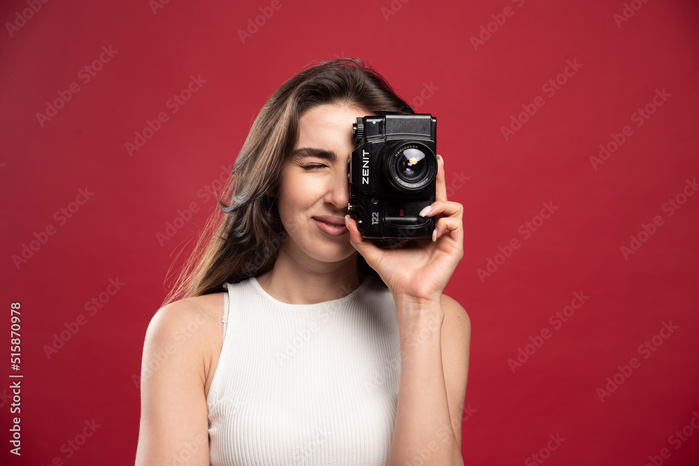 Pretty woman taking photos with a camera on a red background Pretty woman taking photos with a camera on a red background
