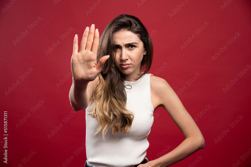 Young pretty brunette woman model showing a stop sign on a red background Young pretty brunette woman model showing a stop sign on a red background