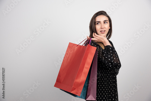 Young woman model carrying a lot of shopping bags on a white background