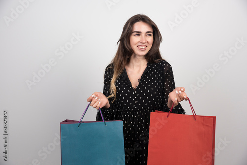 Young woman model carrying a lot of shopping bags on a white background