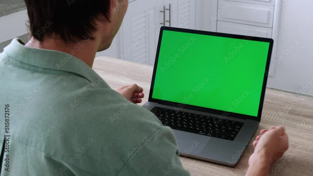 Closeup back view shoot of young business man having a video call on the laptop with green chroma screen indoors at home Closeup back view shoot of young business man having a video call on the laptop with green chroma screen indoors at home