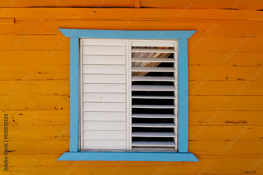 Rustic blue and orange wooden house with wooden window shutters. Dominican Republic. Rustic blue and orange wooden house with wooden window shutters. Dominican Republic.