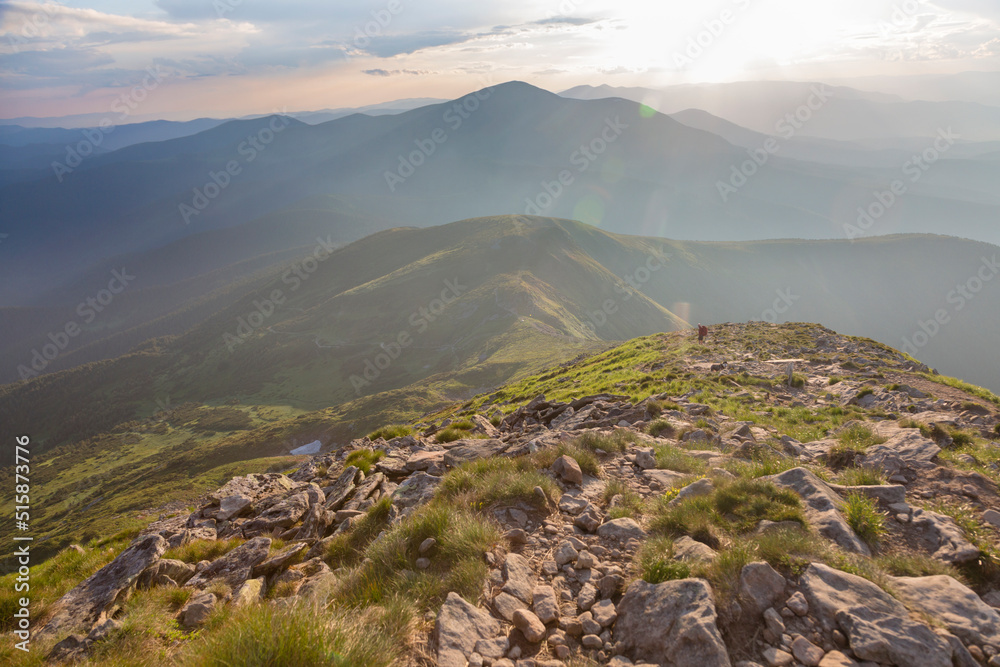 Hiking in the stoned mountains hills during sunset with blue sky and clouds in the Carpathians, Chornohora