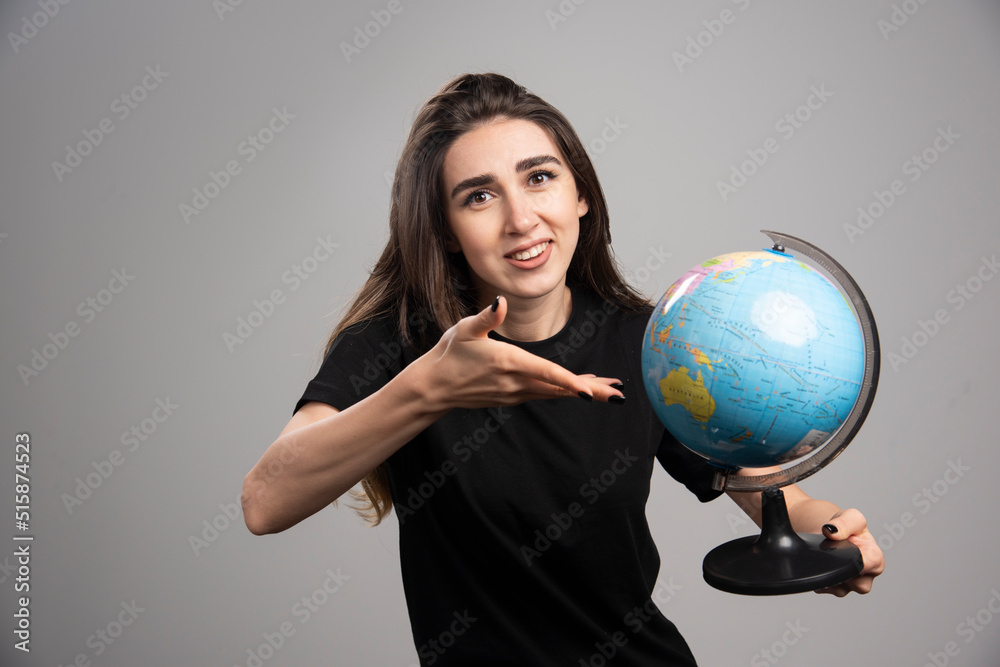Young woman showing globe on gray background Young woman showing globe on gray background