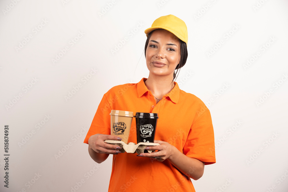 Smiling woman courier holding two cups of coffee Smiling woman courier holding two cups of coffee