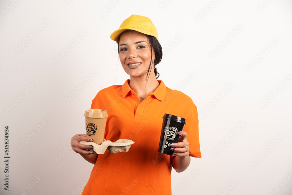 Smiling woman courier offering two cups of coffee Smiling woman courier offering two cups of coffee