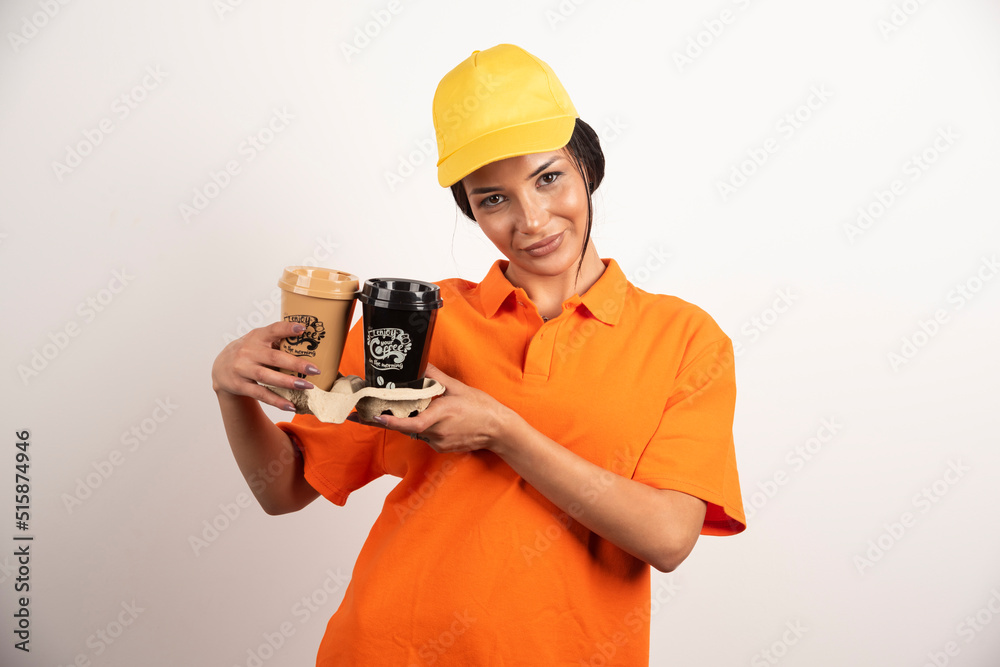 Smiling woman courier holding two cups of coffee Smiling woman courier holding two cups of coffee